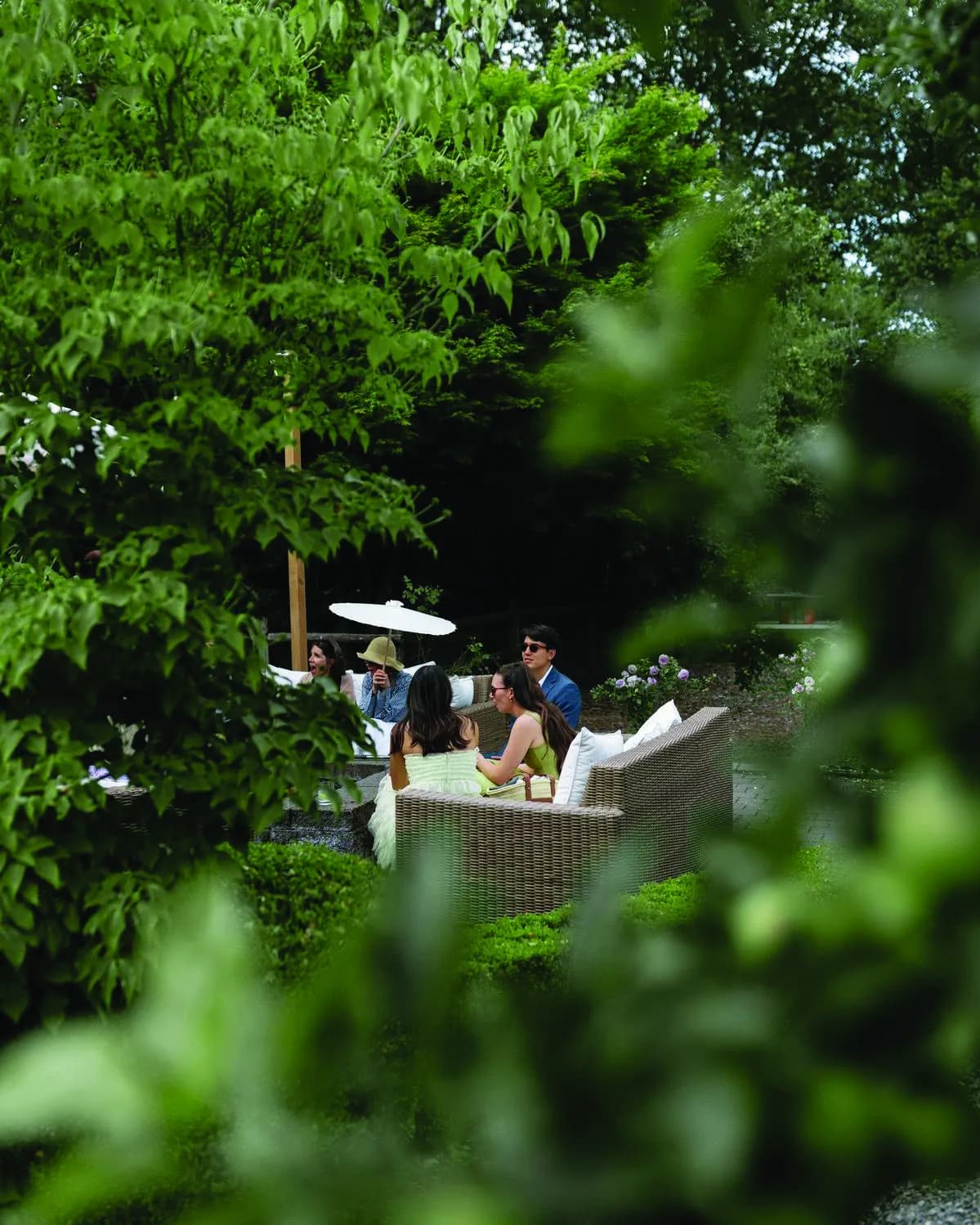 Friends talking on garden lounge chairs surrounded by trees