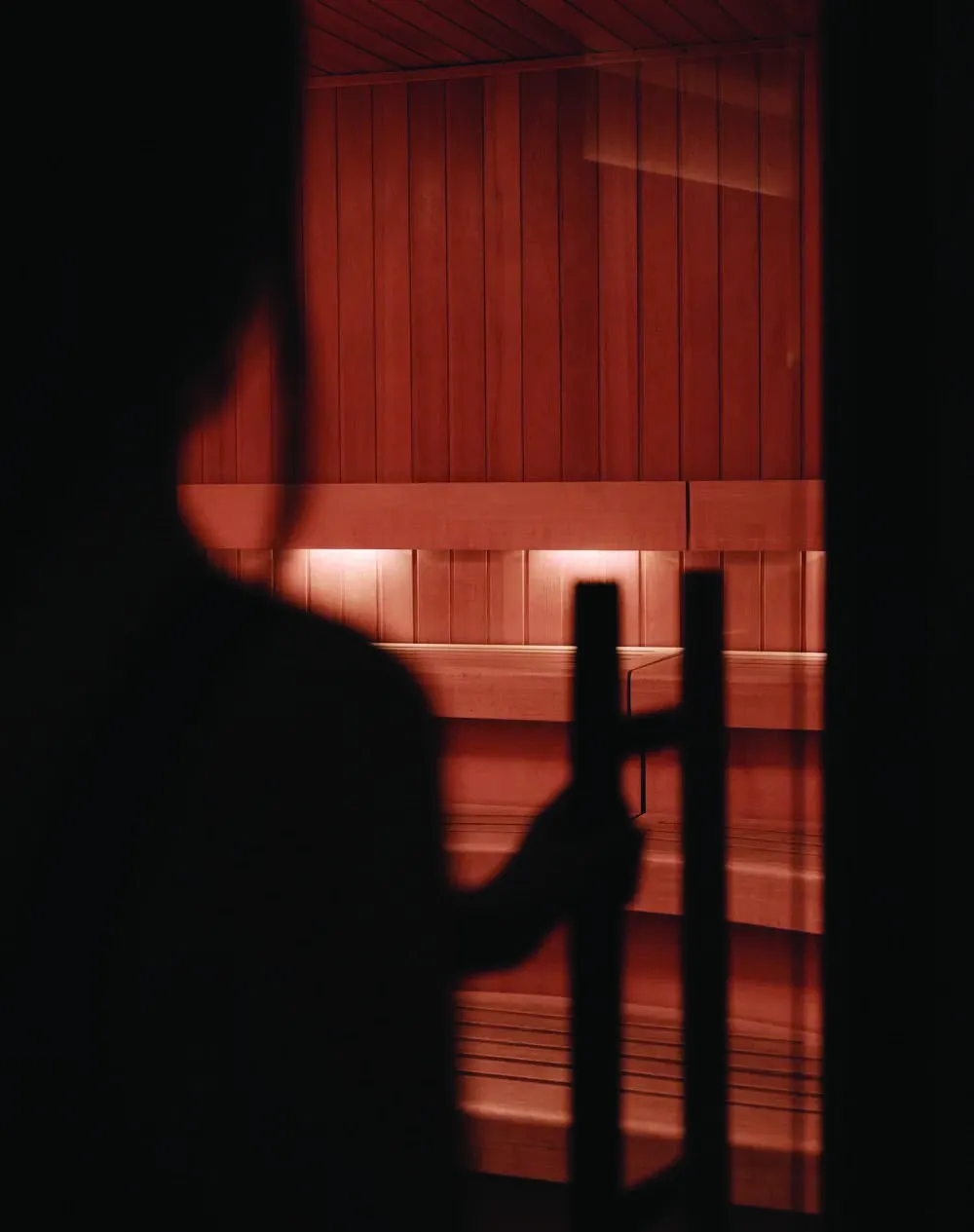 Silhouette at the door of a warmly lit sauna